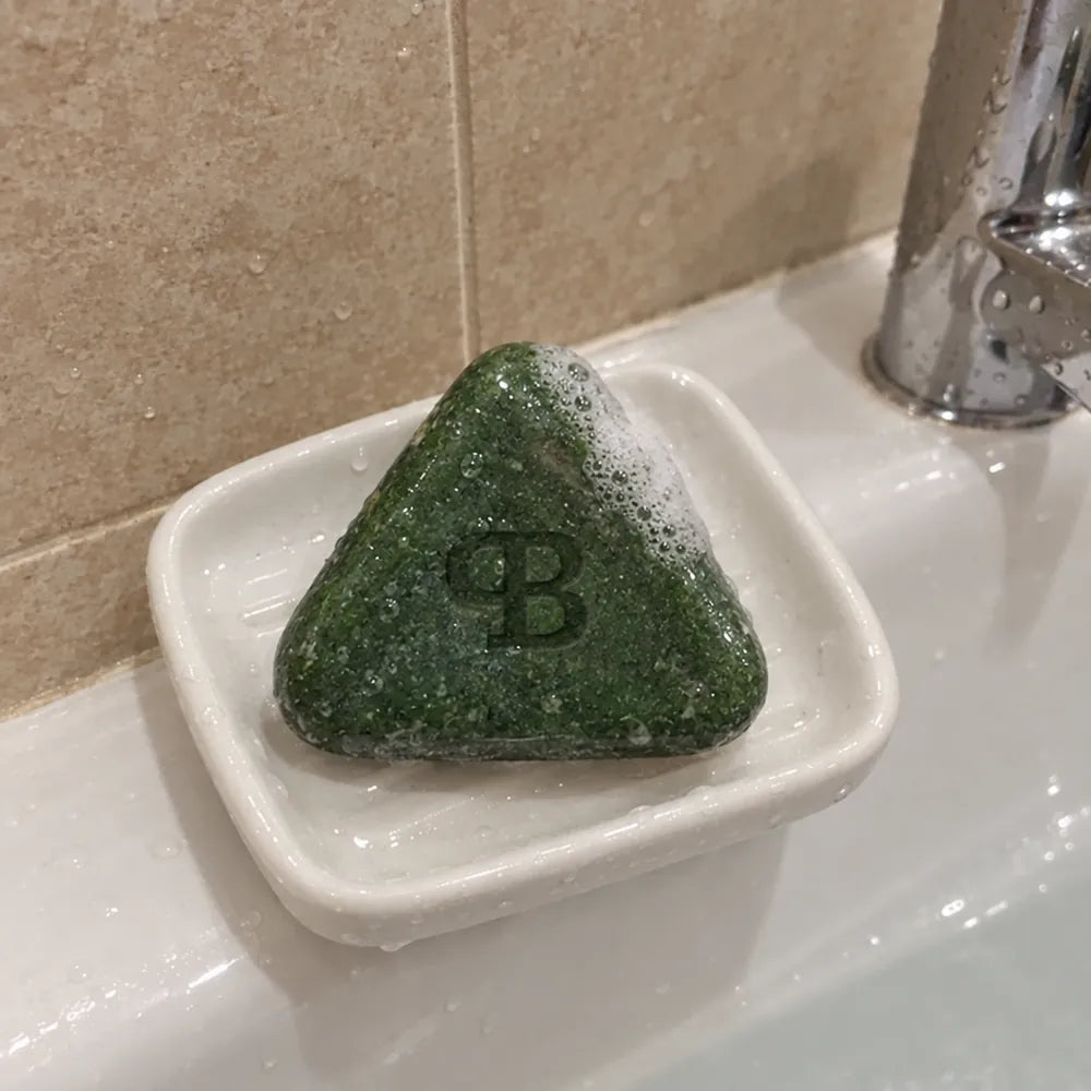 La barre Fraîche Heure mouillée sur un porte-savon blanc, au bord de la baignoire